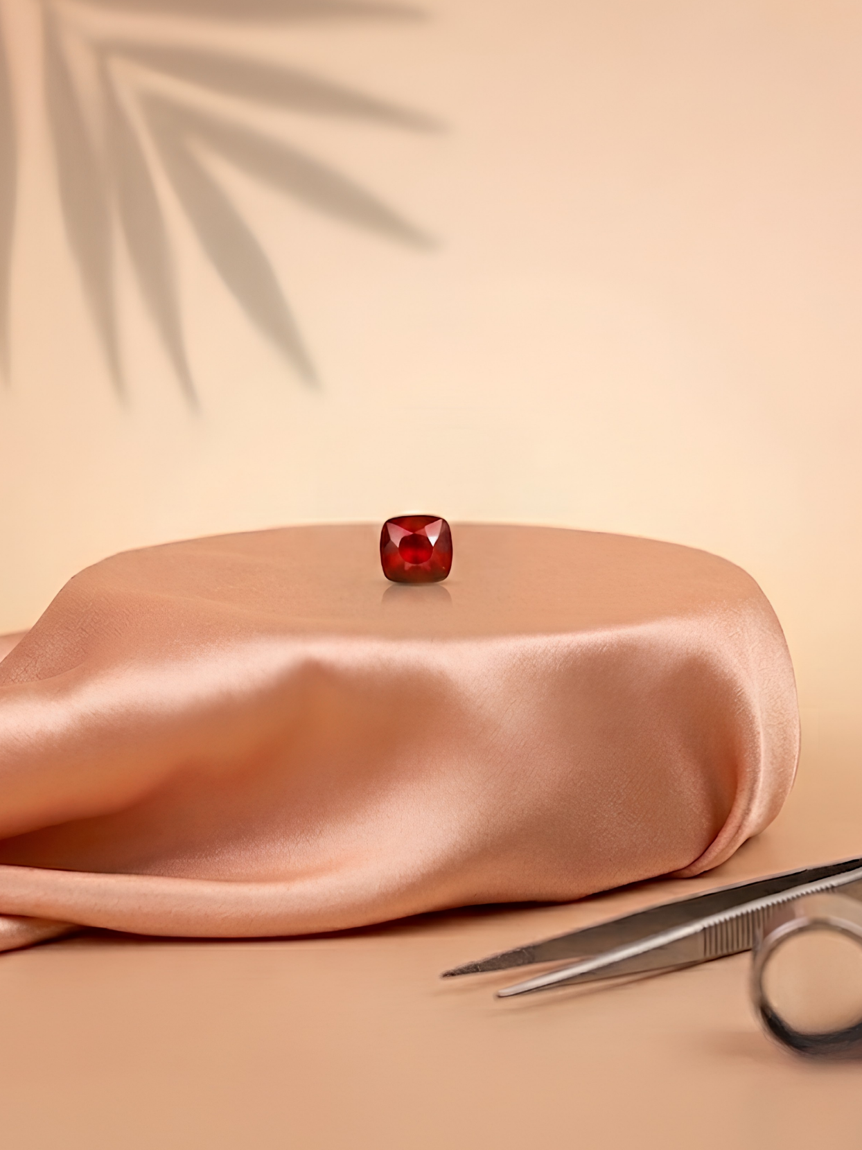 Front lifestyle view of the Mani Monk approx 4-carat Gomed stone, resting elegantly on a peach silk pedestal alongside a jeweler's loupe and tweezers.