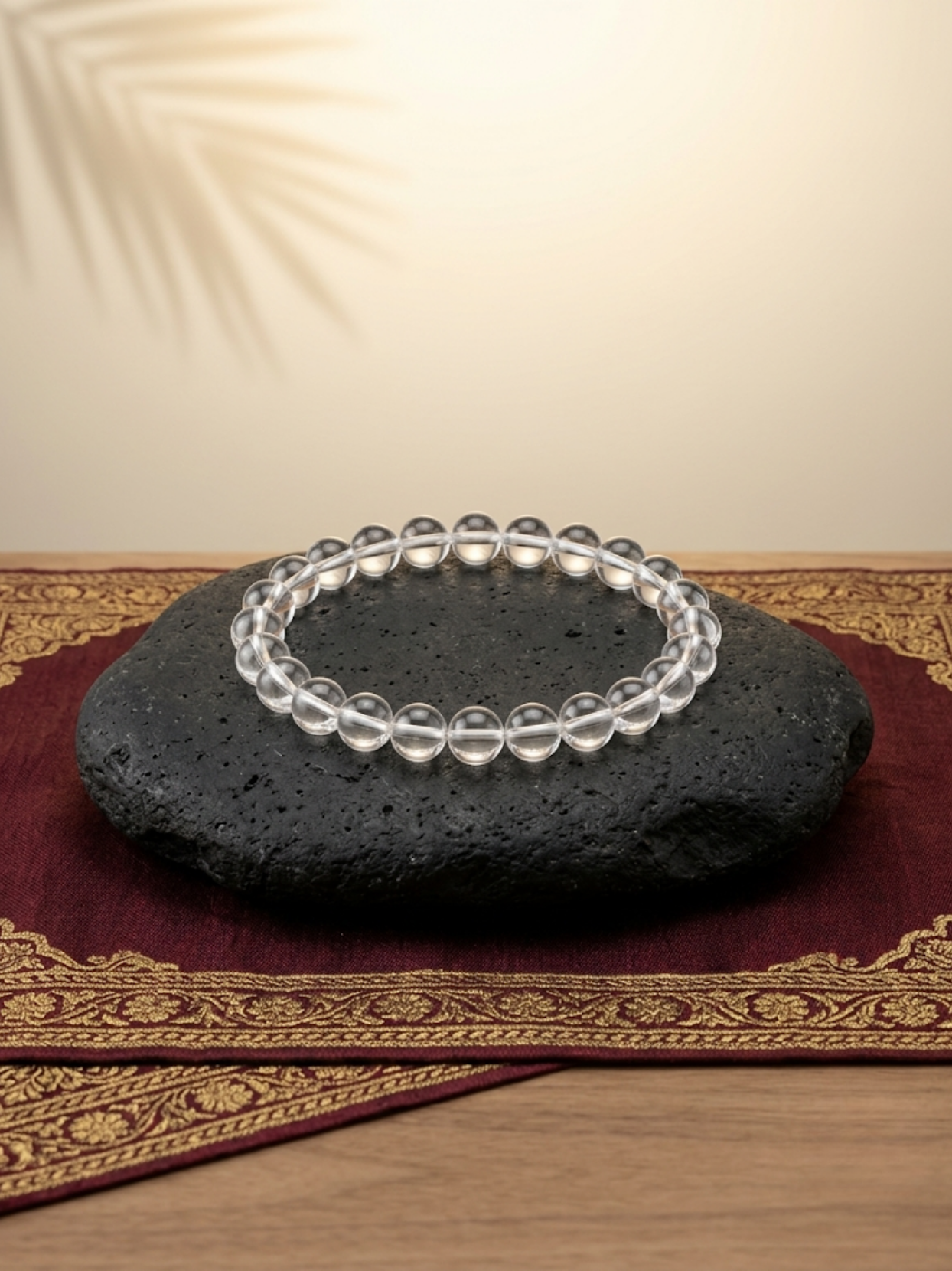 Front flat lay view of the Mani Monk pure round Sphatik 8mm crystal bracelet, beautifully styled on a dark stone and traditional red cloth.